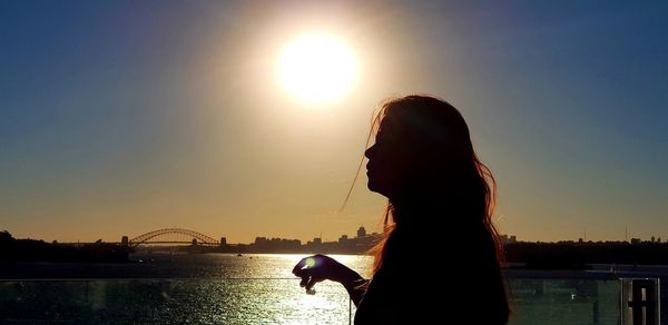 Silhouette woman standing by sea against sky during sunset