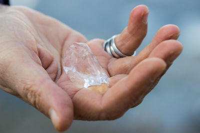 Close-up of hand holding water against sky