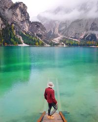 Rear view of man standing by lake