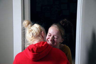 Smiling lesbian woman embracing girlfriend at home