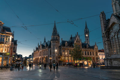 Illuminated buildings in city against sky at dusk