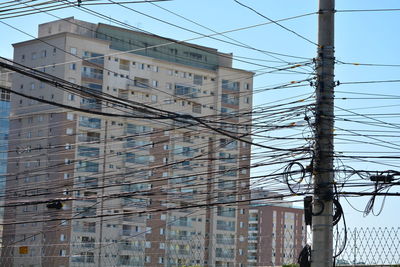 Low angle view of electricity pylon and buildings against sky