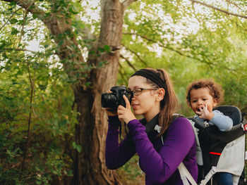 Friends photographing through camera on tree