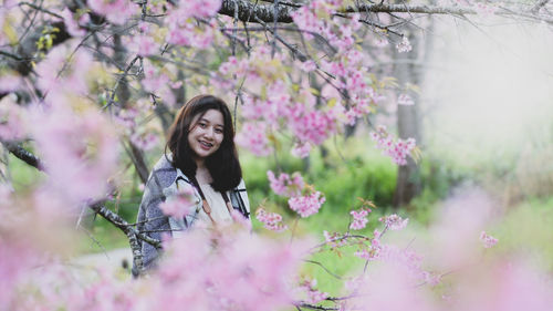 Asian teenage girl travels happily taking pictures with cherry blossoms.