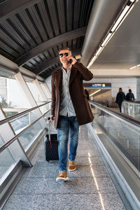 Full length portrait of young man standing on railing