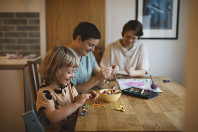 Mothers and daughter making bead jewelry at home