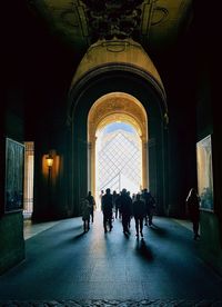 Rear view of people walking in illuminated building