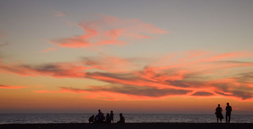 Silhouette of people on beach at sunset