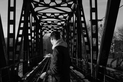 Rear view of man walking on footbridge