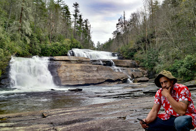 Full length of woman on rock against waterfall