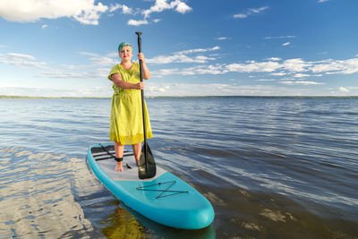 Rear view of woman standing at sea against sky