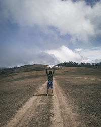 Rear view of man standing on field against sky