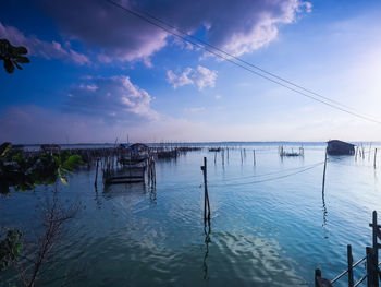 Wooden posts in water against sky