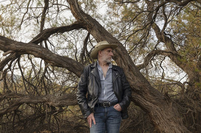 Portrait of adult man in cowboy hat against tree