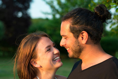 Close-up of smiling young couple against trees