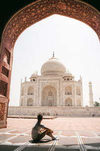 Full length of mans sitting against taj mahal