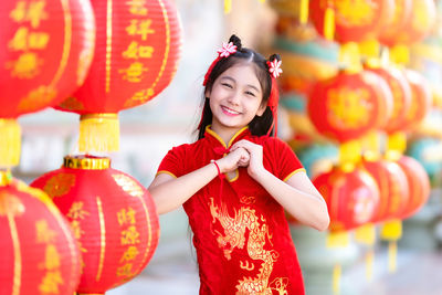 Full length of smiling woman standing in red lantern