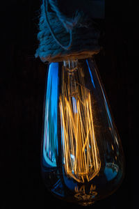 Close-up of illuminated light bulb against black background