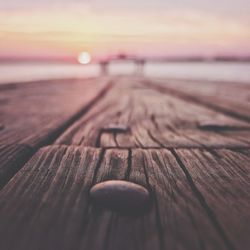 Surface level of wooden jetty at lake against sky during sunrise