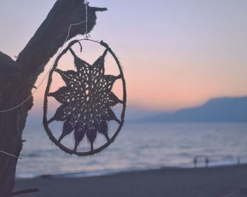 Close-up of silhouette chain on beach against sky during sunset