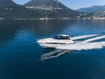 Boat sailing in lake against mountains