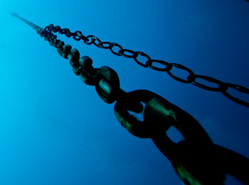 Close-up of chain against blue sky