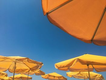 Low angle view of parasol against clear blue sky