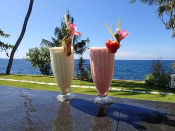 Close-up of drink by swimming pool against sea