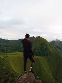 Rear view of man looking at mountain against sky