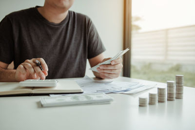 Midsection of man holding camera while sitting on table