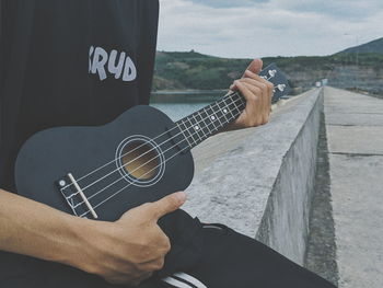 Midsection of man playing guitar