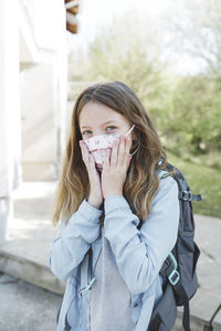 Schoolgirl wearing mask against building