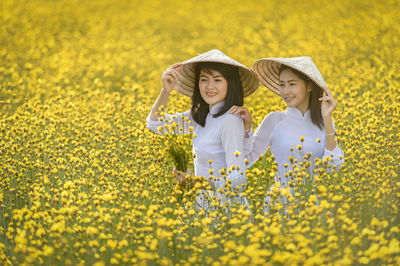 Full length of woman with yellow flowers in field