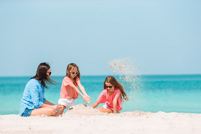 Rear view of women on beach against clear sky