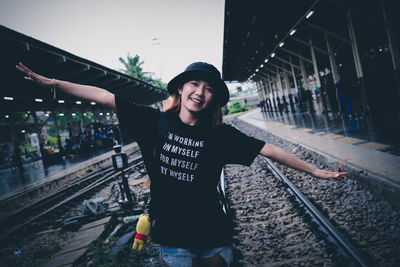 Portrait of smiling young woman standing on railroad track