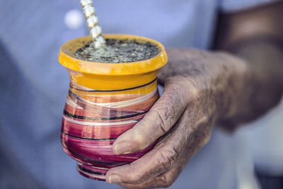 Midsection of person holding yerba mate drink in container