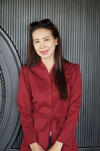 Portrait of smiling mature woman standing against wall