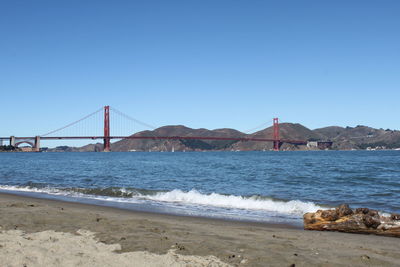 View of suspension bridge over sea against clear sky