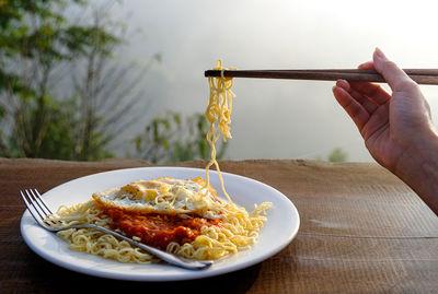 Close-up of hand holding food in plate on table