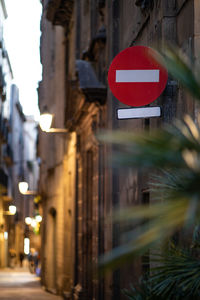 Road sign on street against buildings at night