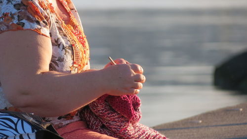 Midsection of woman knitting at beach