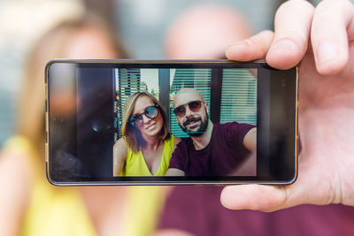 Couple taking selfie while sitting against window 