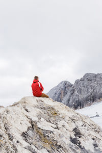 Young millennial man enjoys the views of the alps standing on glacier