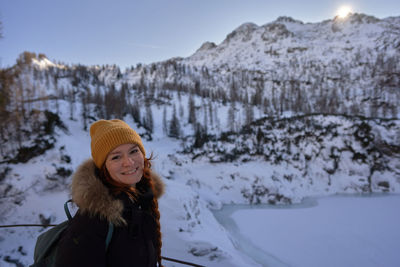 Portrait of smiling young woman standing on snow covered mountain