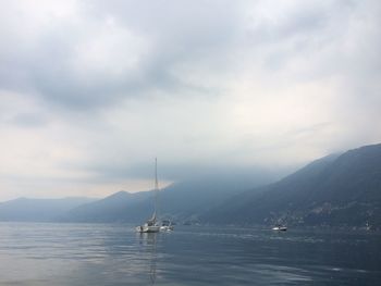 Scenic view of sea by mountains against cloudy sky