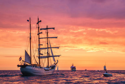 Sailboat sailing on sea against sky during sunset