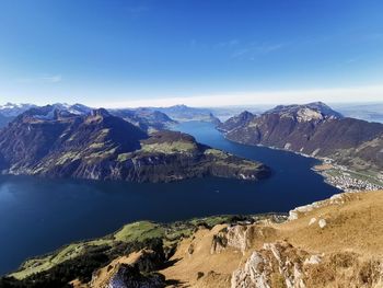 Scenic view of lake and mountains against blue sky