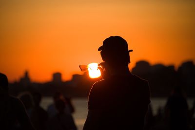 Rear view of silhouette man standing against orange sky