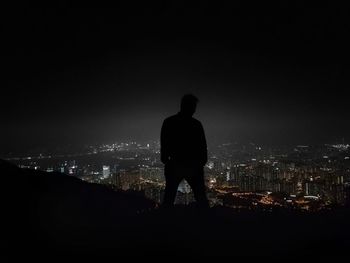 Rear view of man looking at cityscape at night