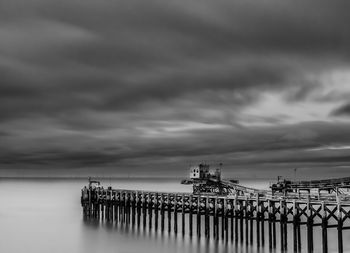 Pier on sea against cloudy sky